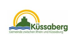 Das Bild zeigt das Logo der Gemeinde Küssaberg mit einer grünen Burg, einem gelben Halbkreis und blauen Wellen, ergänzt durch den Text "Gemeinde zwischen Rhein und Küssaburg".