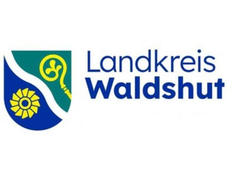 links im Bild blaues Wappen, welches in der Mitte mit diagonalen Wellen getrennt ist, in der linken Hälfte ein gelbes Mühlrad oder Wasserrad und in der rechten Wappenhälfte ein gelbes Zepter, alles auf weißem Hintergrund, rechts im Bild ein blauer Schriftzug Landkreis Waldshut