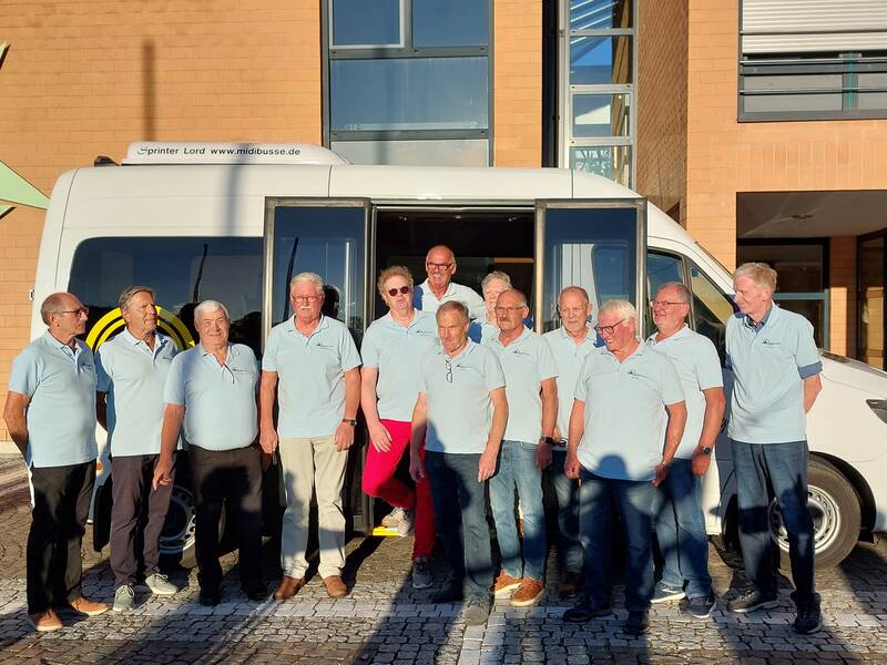 das Bild zeigt die Gruppe der ehrenamtlichen Bürgerbusfahrer stehend vor dem Bürgerbus, im Hintergrund ist das Rathausgebäude zu sehen, angestrahlt von der Abendsonne 